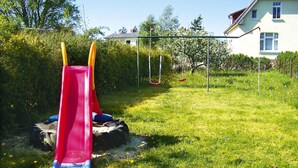 Ein Spielplatz mit rotem Rutsche und Schaukeln auf einer grünen Wiese.