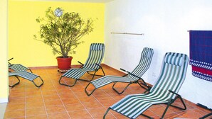 Ein Zimmer mit vier gestreiften Lounge-Stühlen, einer Topfpflanze und einem blau-roten gemusterten Handtuch an der Wand.