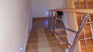 A staircase with a wooden handrail and metal balusters, leading to a landing with a potted plant. - Holiday Home in Dziwnowek by Baltic Beach (Dziwnów)
