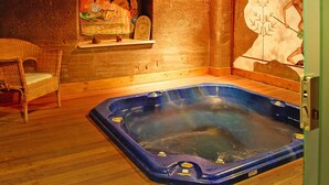 Un bain à remous dans une pièce en bois, avec une fresque murale et un fauteuil en osier.