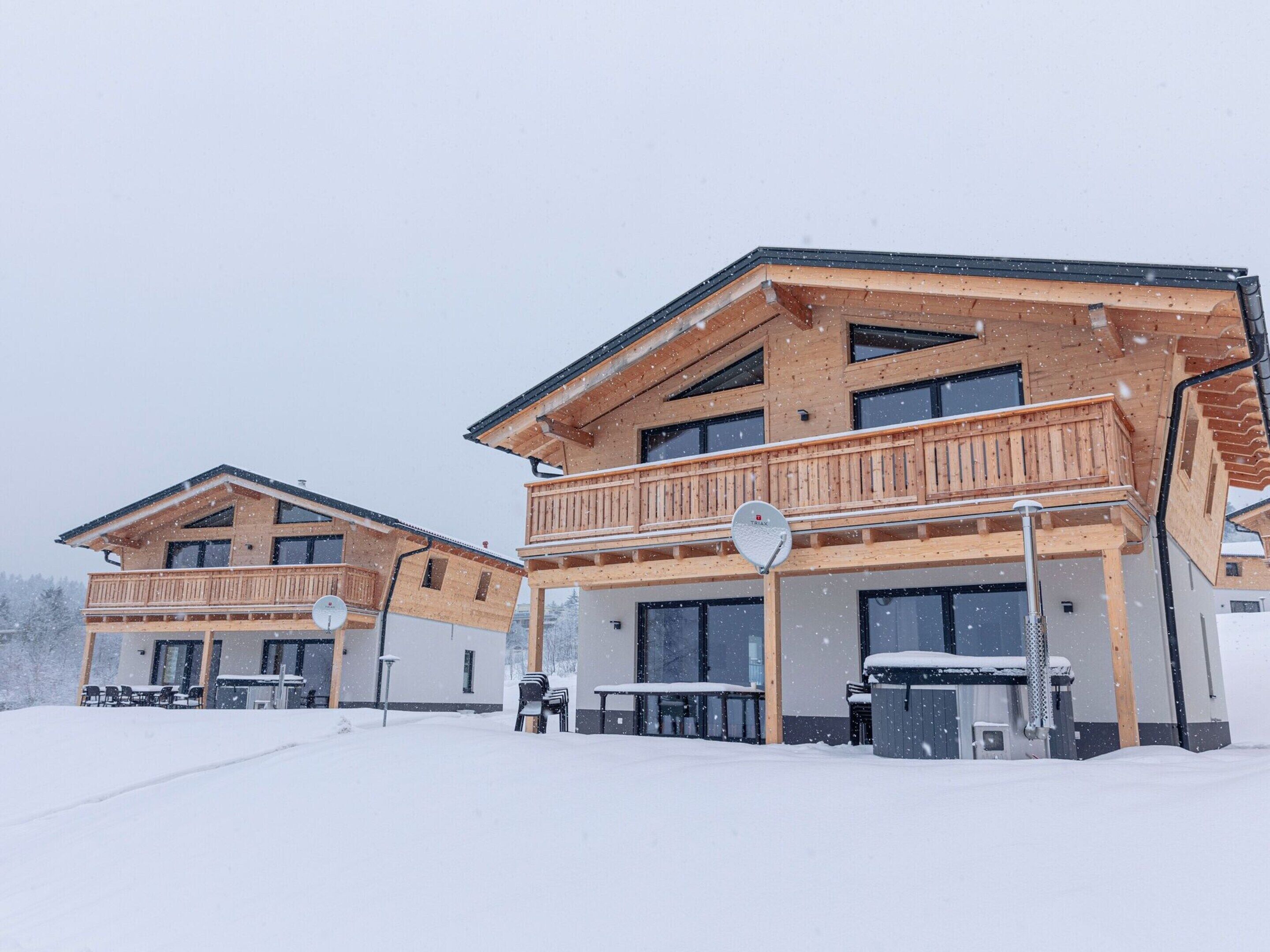 Un chalet en bois doté d’un balcon, d’un jacuzzi et d’un espace extérieur am énagé et abrité.