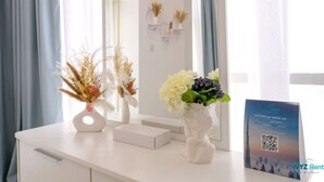 Zona de recepción de un hotel con un mostrador blanco, dos jarrones con flores y un código QR para WYZ Rent.