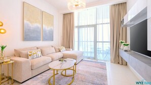 Una sala de estar moderna con un sofá beige, una mesa de centro redonda y un televisor de pantalla plana grande.