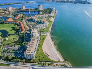 An aerial view of a coastal hotel area with multiple buildings, a beach, and a marina.