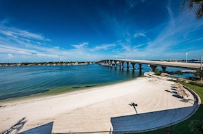 A beach with a large concrete structure, likely a bridge, extending over a body of water.