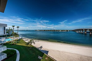Una propiedad frente a la playa con piscina, palmeras y vistas al océano y un puente.