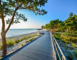 A coastal walkway with a metal railing, leading to a beach. - Cottage in Ustronie Near Sandy Beach (Ustronie Morskie)