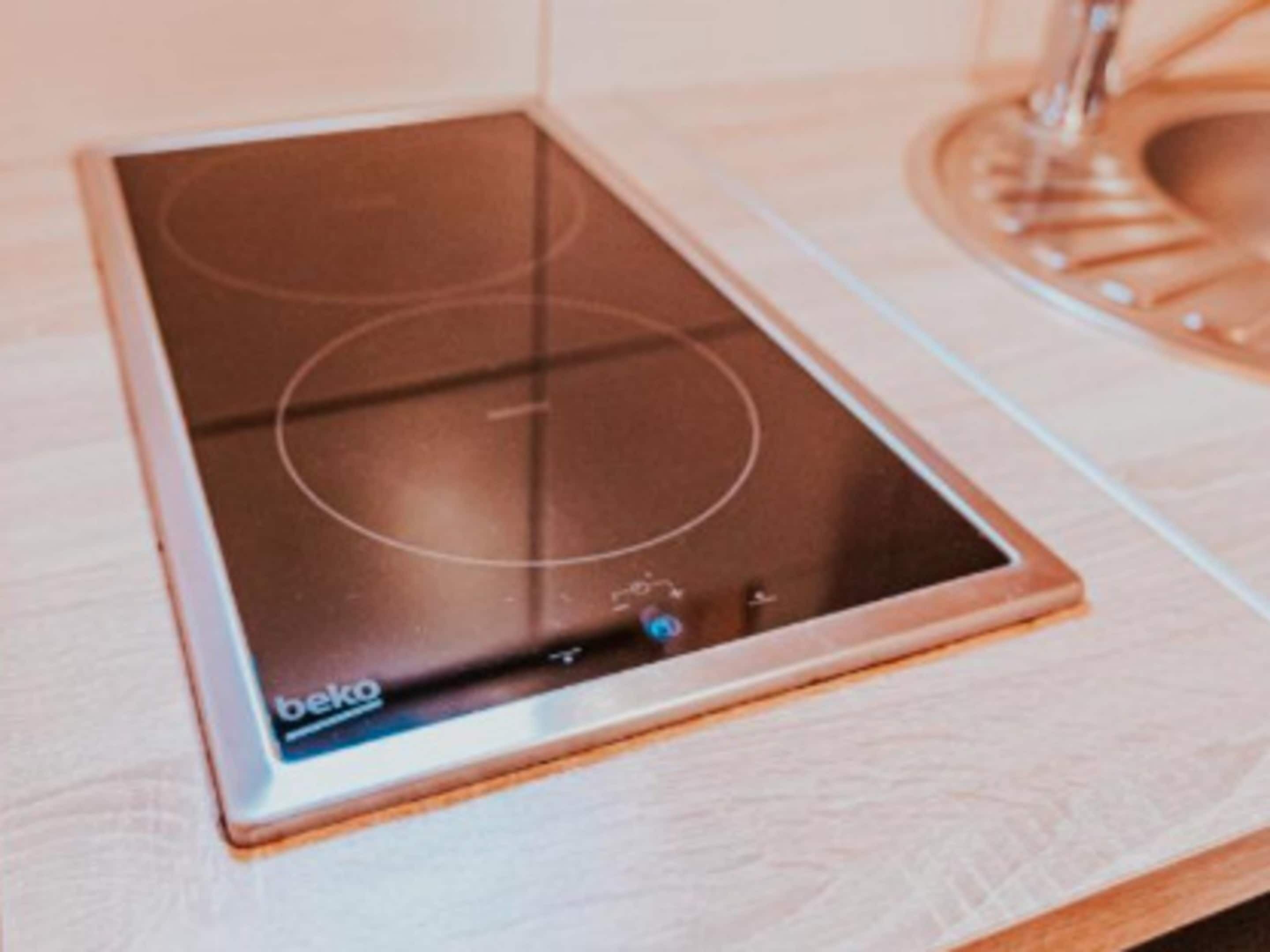 A beko induction cooktop on a wooden countertop.