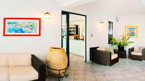 A spacious living area with a sofa, wicker chairs, a large vase, and wall art. - Holiday Flat in Pretty Residence With Communal Pool in Pietra Ligure (Pietra Ligure)