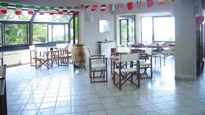 A spacious room with tiled flooring, multiple wooden chairs, a large vase, and flags on the ceiling. - Holiday Flat in Pretty Residence With Communal Pool in Pietra Ligure (Pietra Ligure)