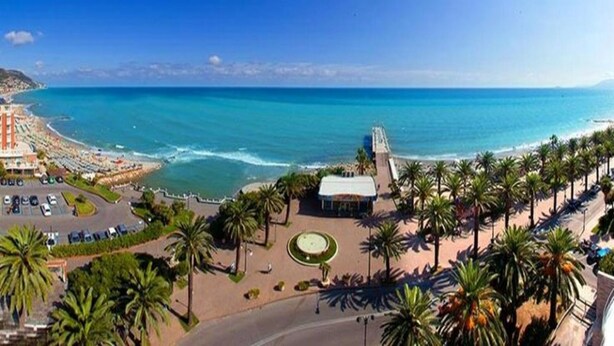 Une vue sur la côte, avec une plage, des palmiers et un espace de stationnement.