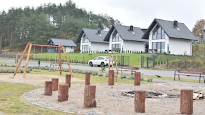 Ein Wohngebiet mit modernen Häusern, einem Spielplatz und einem geparkten Auto.