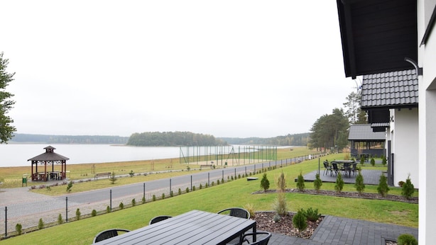 Eine Terrasse mit Tisch und Stühlen mit Blick auf einen See, einem Pavillon und einem Sportplatz.