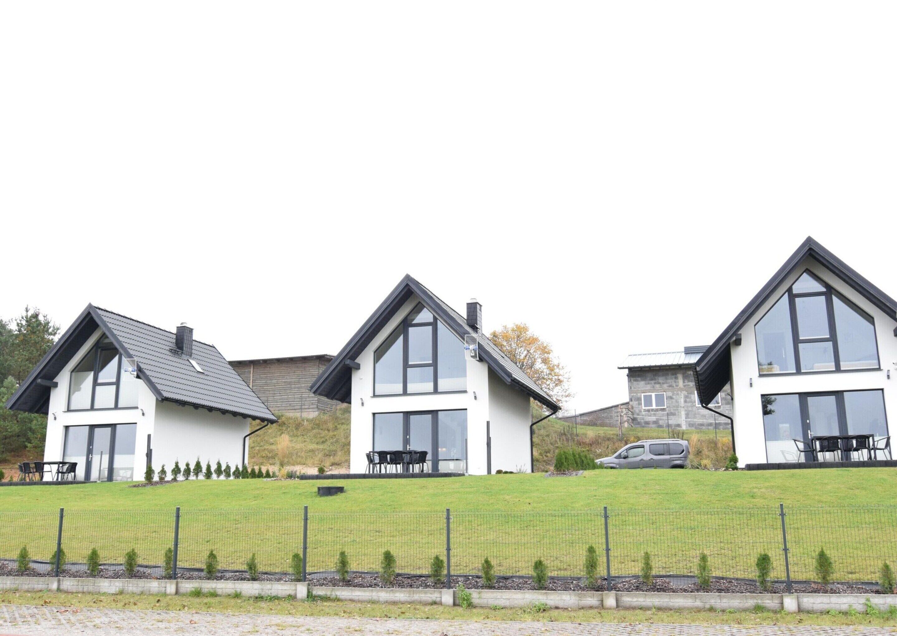 A row of modern houses with large windows and a grassy front yard.