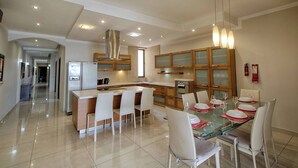 A modern kitchen with a central island, white chairs, and a dining table set for six.