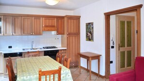 Una cocina con armarios de madera, una mesa de comedor con sillas, una mesita auxiliar y un sofá rojo.
