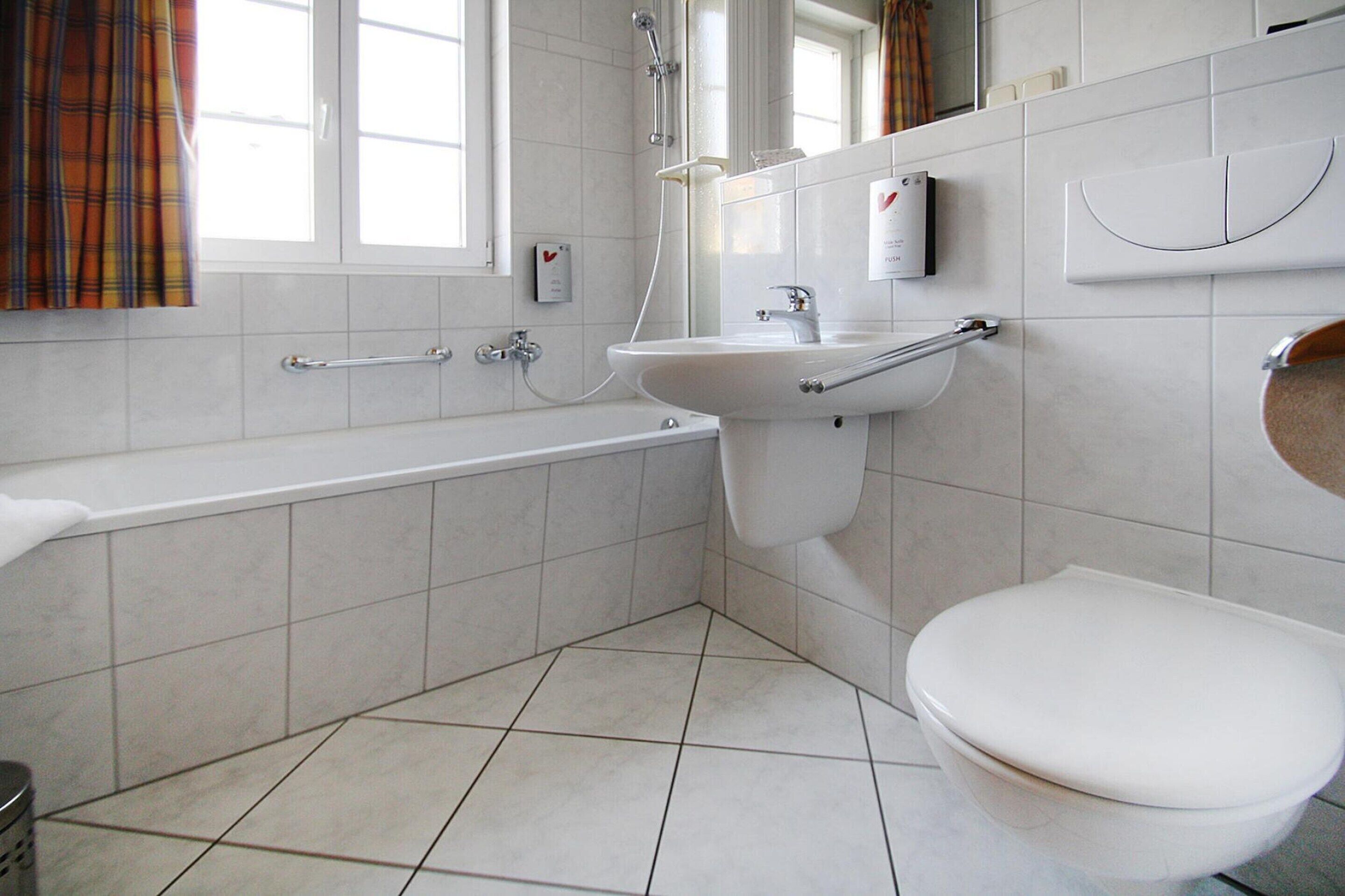 A modern bathroom with a bathtub, sink, and toilet.
