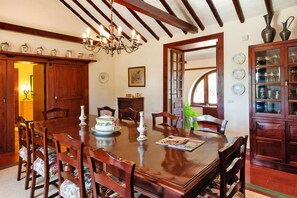 A dining room with a wooden table, chairs, a chandelier, and a cabinet with glass doors. - Villa Mansion Bandama With Pool in Santa Brigida (Santa Brigida)