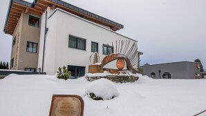 A modern building with a snow-covered entrance and a metal sculpture. - Apartment in Neukirchen by Wildkogelbahn (Neukirchen am Grossvenediger)