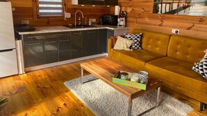 A cozy cabin interior with a kitchen, a sofa, and a coffee table. - Holiday Home in Stepnica With Sauna & Jacuzzi (Stepnica)