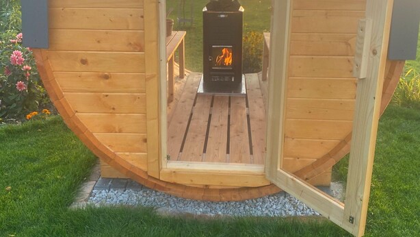 A wooden cabin with a circular design, featuring a central wood-burning stove and a wooden deck. - Holiday Home in Stepnica With Sauna & Jacuzzi (Stepnica)