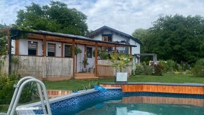 A residential property with a swimming pool, wooden deck, and a house with a porch. - Holiday Home in Stepnica With Sauna & Jacuzzi (Stepnica)