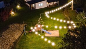 A backyard with a play structure, string lights, and a house in the background. - One-story House With a Terrace, Kolobrzeg (Kolobrzeg)