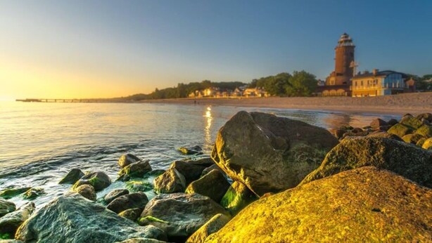 A coastal scene with a lighthouse, rocky shoreline, and buildings in the background. - One-story House With a Terrace, Kolobrzeg (Kolobrzeg)