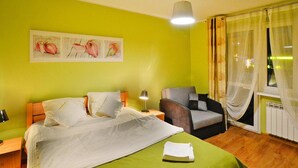 A hotel room with a bed, a chair, a desk, and a window with curtains. - 2-room Holiday Apartment Close to the Beach (Kołobrzeg)