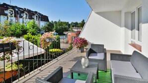 A balcony with wicker furniture, a green mat, and potted plants. - 2-room Holiday Apartment Close to the Beach (Kołobrzeg)