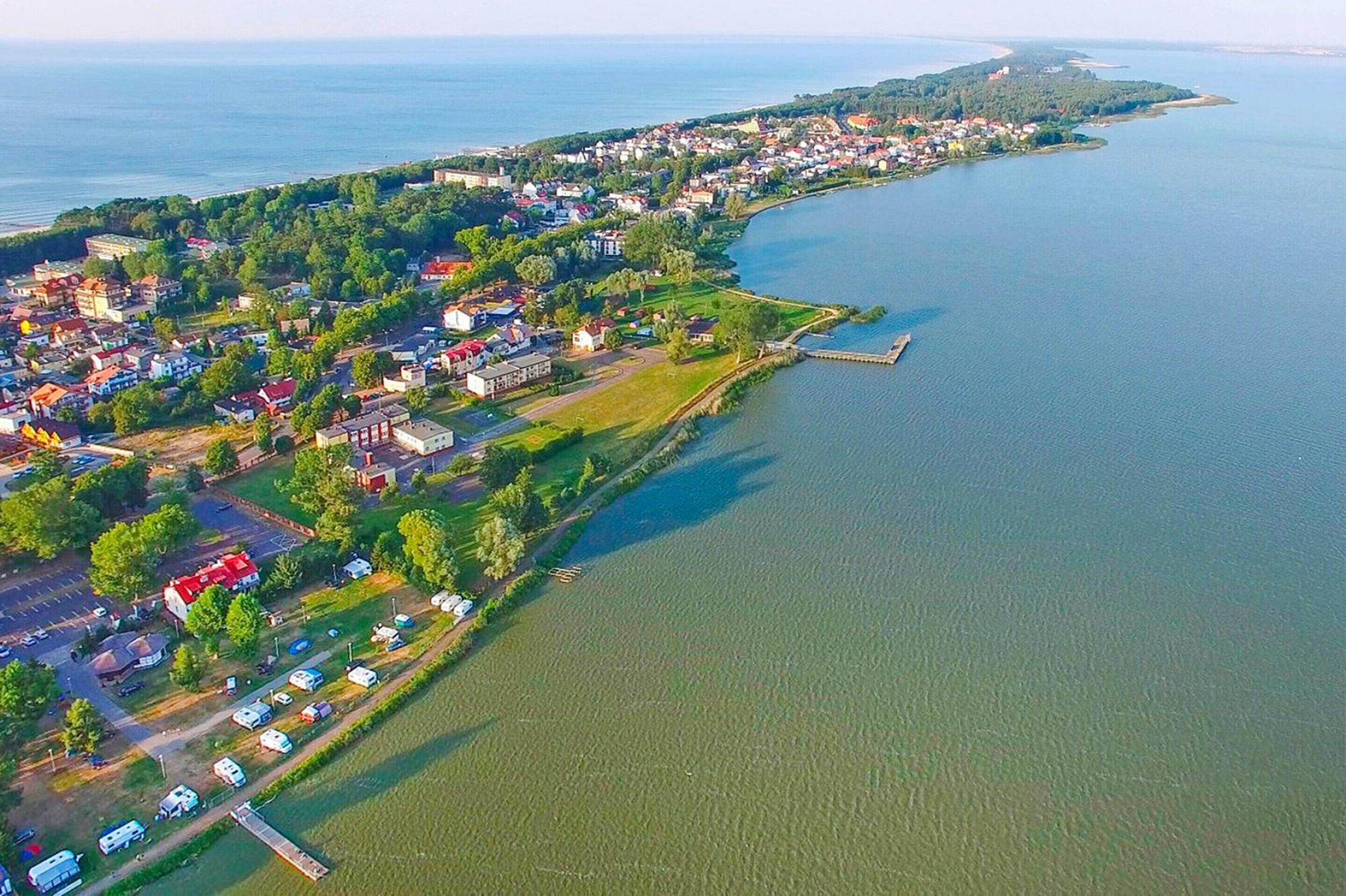 An aerial view of a lakeside town with residential buildings, a marina, and a dock.