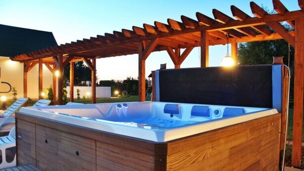 A wooden hot tub under a pergola with a wooden deck and lounge chairs. - Holiday Home by Lake Jamno With Pool (gmina Sianów)