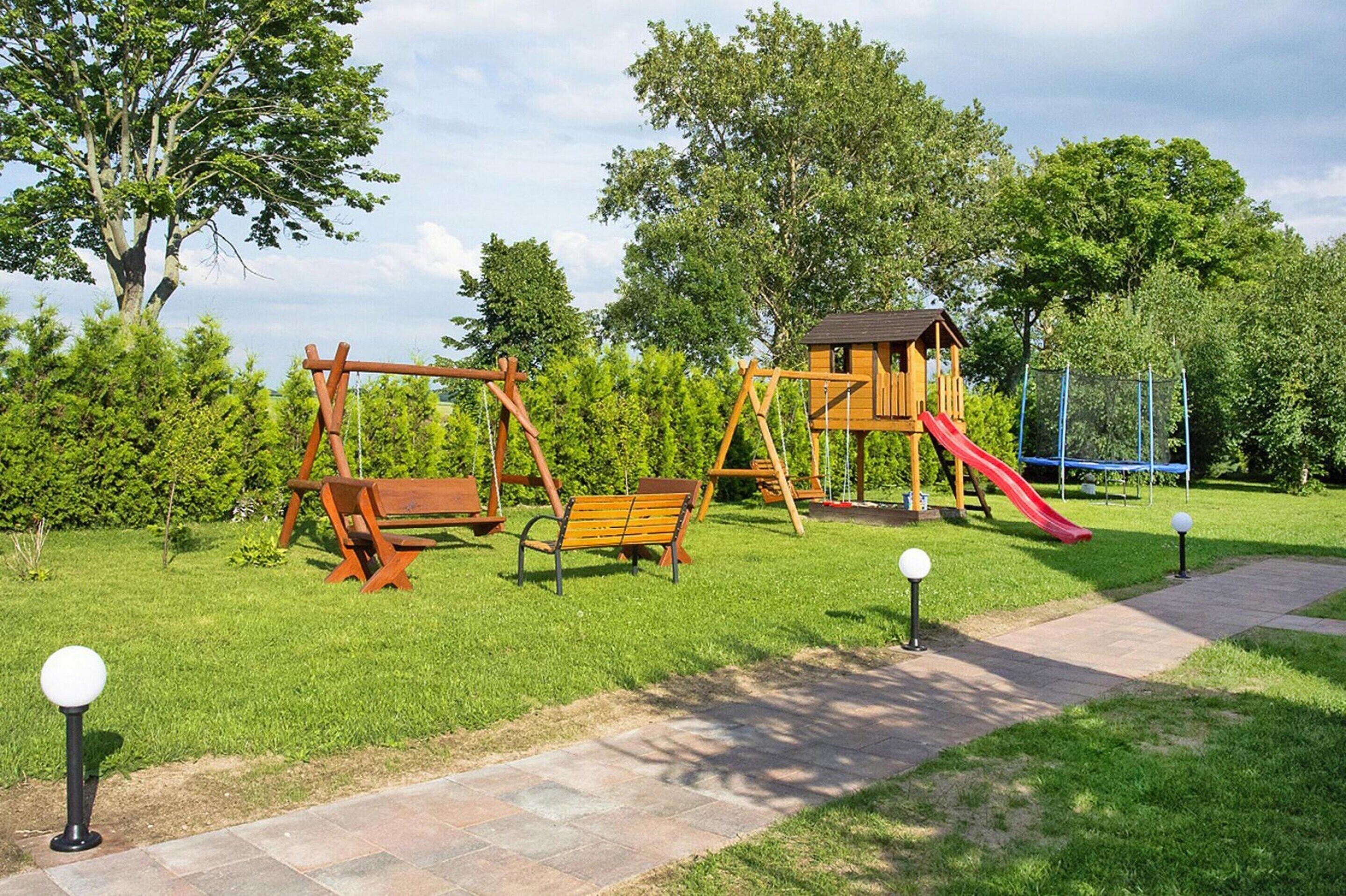 A playground with swings, a slide, and a wooden playhouse.