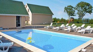 A rectangular swimming pool with a tiled deck, surrounded by white lounge chairs and a small inflatable pool toy. - Holiday Home by Lake Jamno With Pool (gmina Sianów)