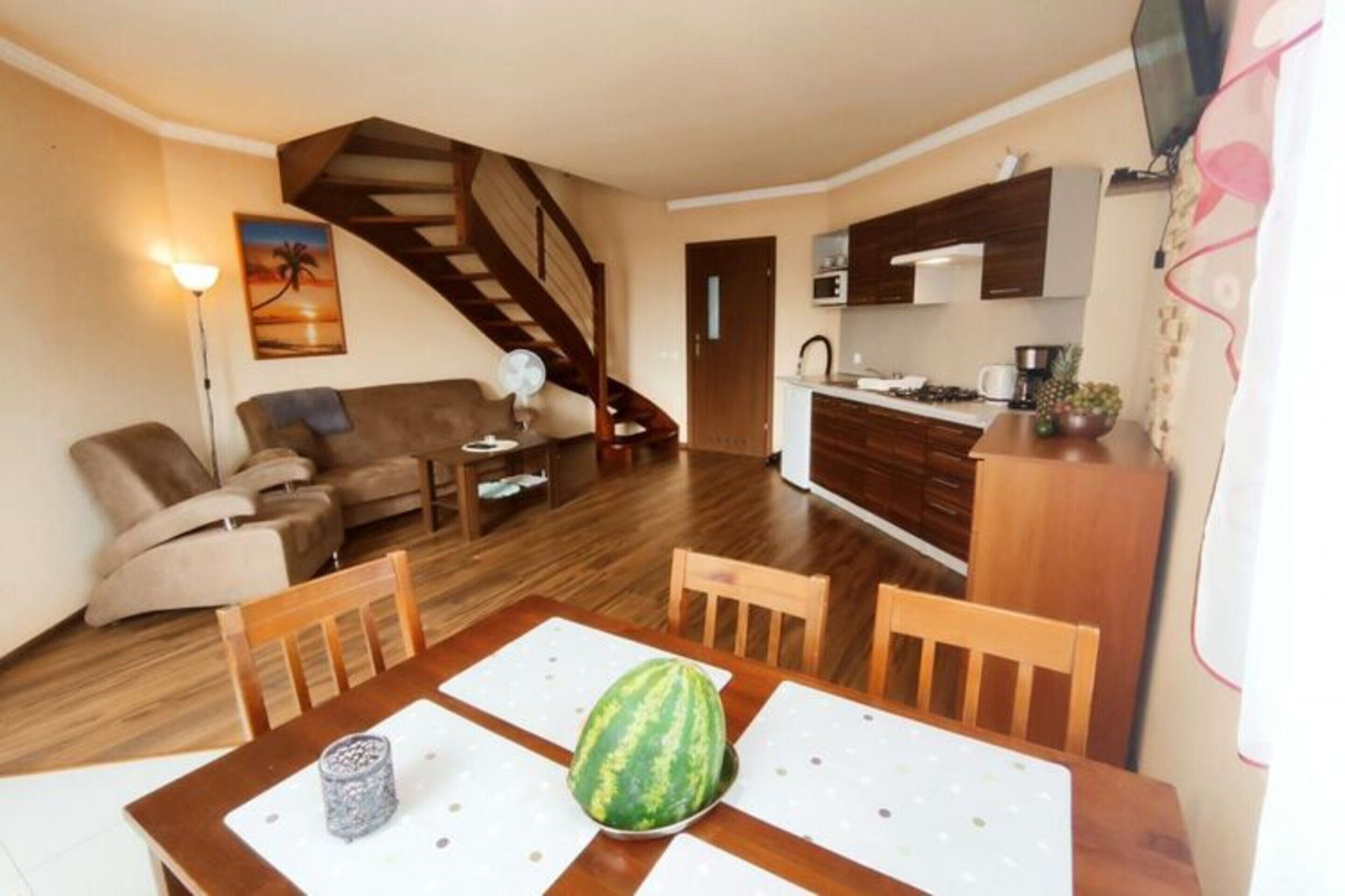 A compact living space with a dining area, kitchenette, and a staircase.