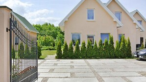 A two-story building with a beige facade, multiple windows, and a gated entrance. - Holiday Home by Lake Jamno With Pool (gmina Sianów)