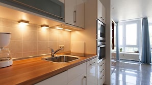 A modern kitchen with a stainless steel sink, wooden countertop, and built-in appliances. - Ferienwohnung in Cuxhaven-duhnen (Cuxhaven)