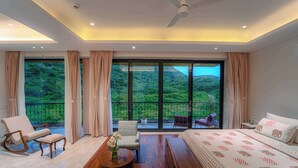 A bedroom with a large bed, a seating area with chairs, a coffee table with flowers, and a balcony with a view of greenery. - Artisav House-A Luxury Boutique Stay (Amer)