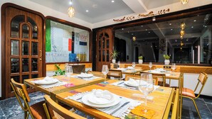 A restaurant with wooden furniture, tables set with plates and glasses, and a view through large windows. - Artisav House-A Luxury Boutique Stay (Amer)