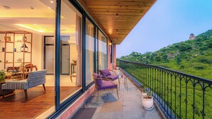 A modern hotel room with a balcony, large windows, and a view of a green hillside. - Artisav House-A Luxury Boutique Stay (Amer)
