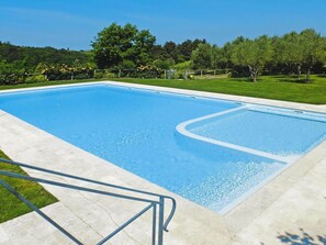 A rectangular swimming pool with a clear blue water surface, surrounded by a concrete deck and a grassy area with trees. - Apartment in Tuscany With Pool & Golf (Gambassi Terme)