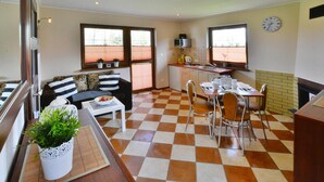 Espaço compacto com área de refeições, cozinha compacta e sofá com almofadas listradas.