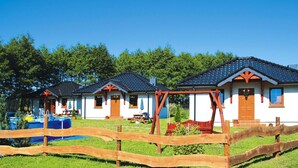 Fileira de cabanas com um muro de madeira ao primeiro plano, cada uma com um telhado de design único e uma pequena varanda.