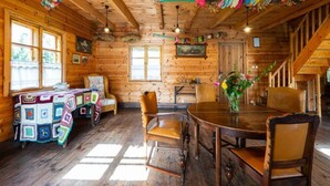 Un interior de cabaña acogedor, con paredes de madera, una mesa redonda para comer y una zona de estar confortable.