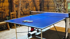 Una mesa de ping pong en una habitación rústica con paredes de madera y ruedas grandes.