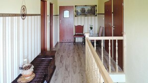 Un corridoio con pavimento in legno, un tavolo da pranzo con una torta, una sedia e una scala con ringhiera in legno.