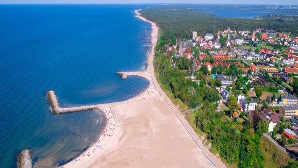 An aerial view of a coastal town with a sandy beach, a pier, and residential buildings. - Apartment in Jaroslawiec Near the Beach (Postomino)