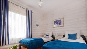A room with two beds, wooden flooring, a nautical-themed wall decoration, and a framed picture. - Apartment in Jaroslawiec Near the Beach (Postomino)