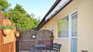 A patio with a table and two benches, surrounded by a wooden fence and potted plants. - Holiday Home in Stepnica for 6 Persons (Stepnica)