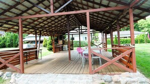 Un espace extérieur abrité, doté d’une terrasse en bois, d’un chemin en pierre et d’un aménagement avec des sièges.